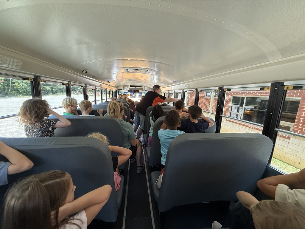 A bus driver on a school bus talks to a group of first graders about bus safety.