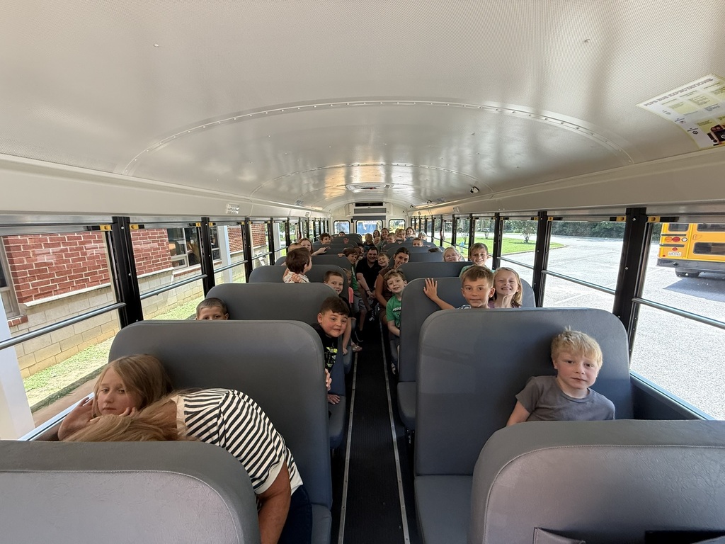 A group of first graders listen to a bus driver on a school bus talk about bus safety.
