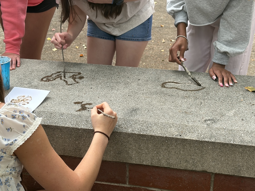 High school art students paint art on stone in a lesson inspired by prehistoric art.