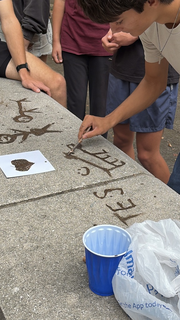 High school art students paint art on stone in a lesson inspired by prehistoric art.