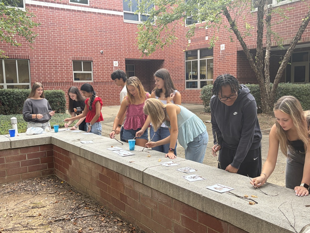 High school art students paint art on stone in a lesson inspired by prehistoric art.