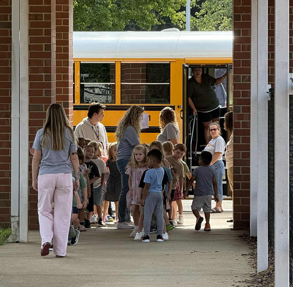 A line of kindergarten students and teachers line up for a lesson on school bus safety.