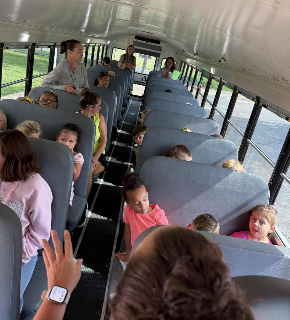 A line of kindergarten students and teachers on a bus listen to a lesson on school bus safety.