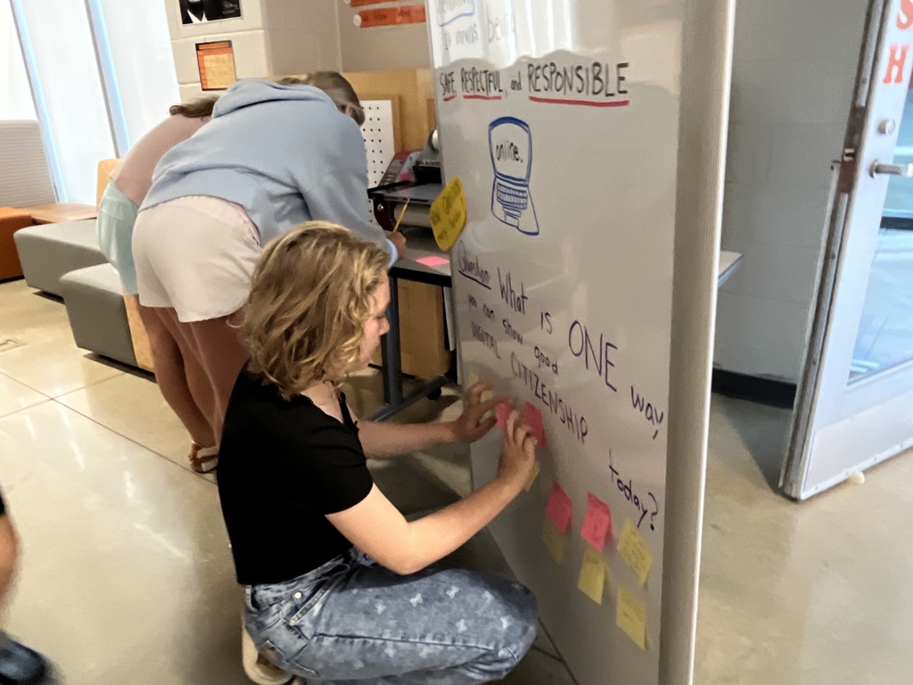 Students answer a question on a board prompting them to think about digital citizenship.