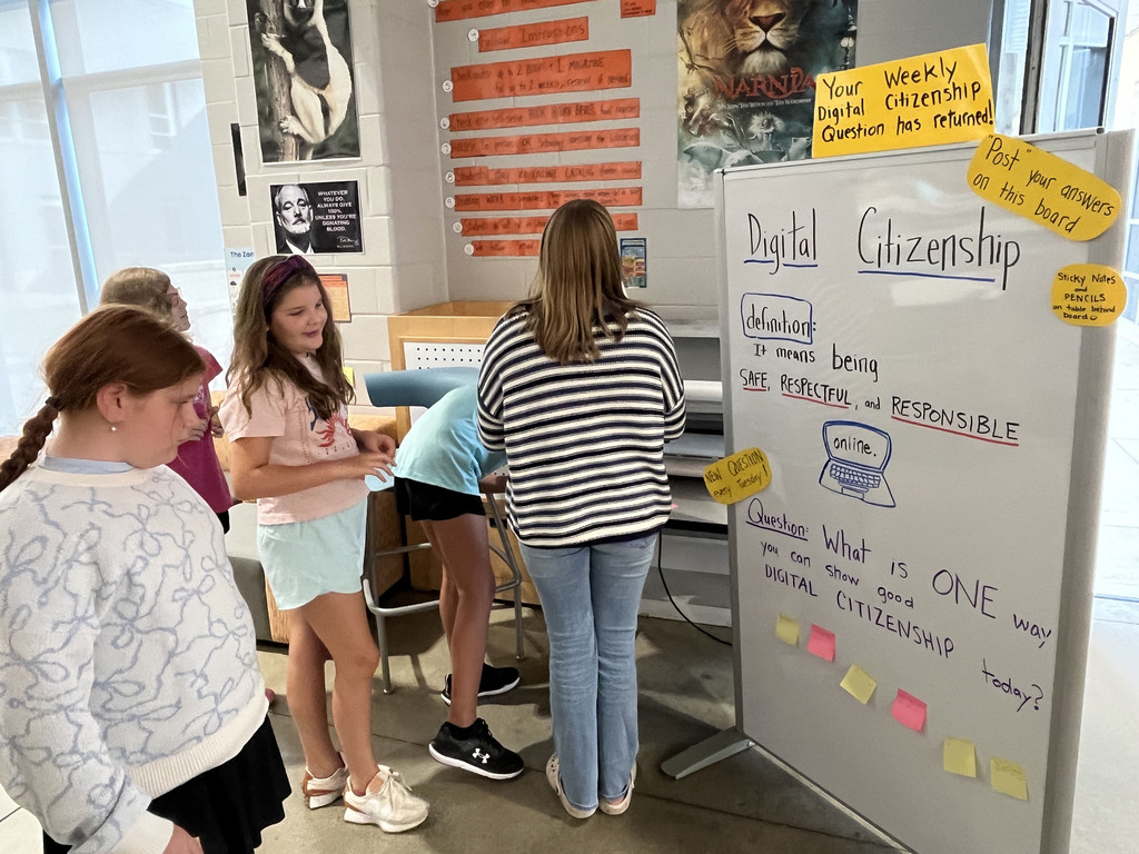 Students answer a question on a board prompting them to think about digital citizenship.