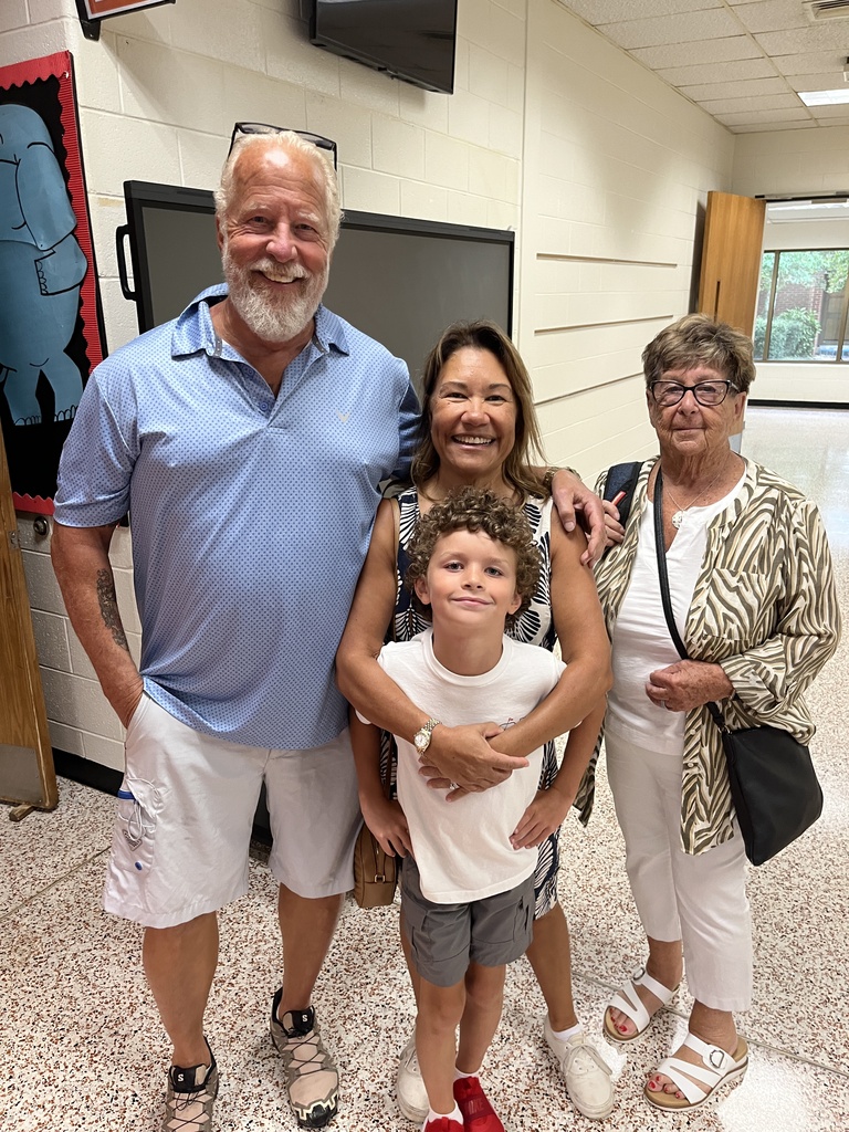 Three adults and a child pose for a photo at an elementary open house. 