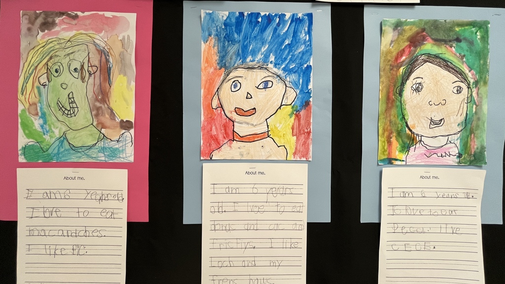 Photo of student work posted in a hallway. Features self portraits they drew and a writing assignment to tell about themselves.
