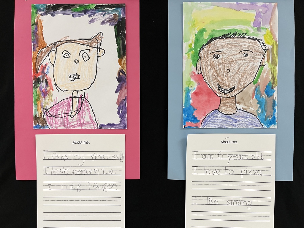 Photo of student work posted in a hallway. Features self portraits they drew and a writing assignment to tell about themselves.