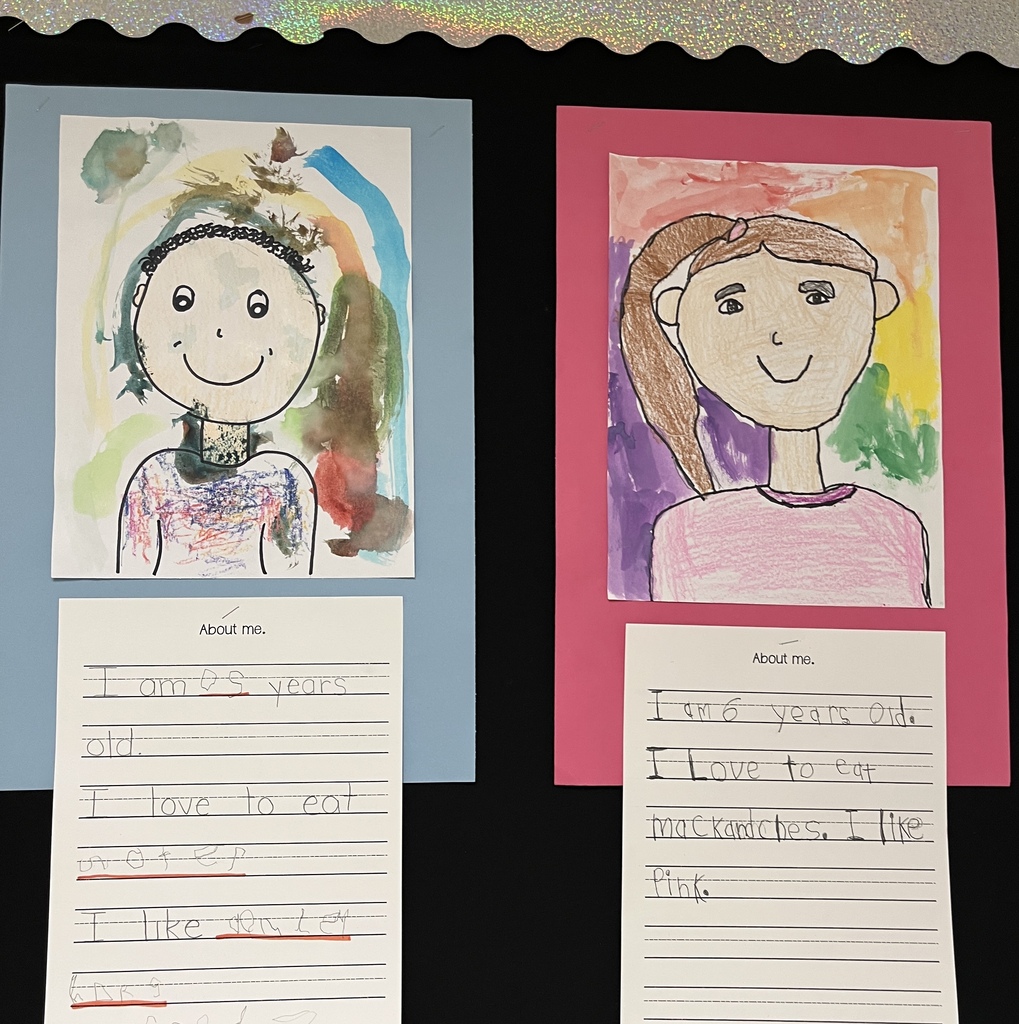 Photo of student work posted in a hallway. Features self portraits they drew and a writing assignment to tell about themselves.