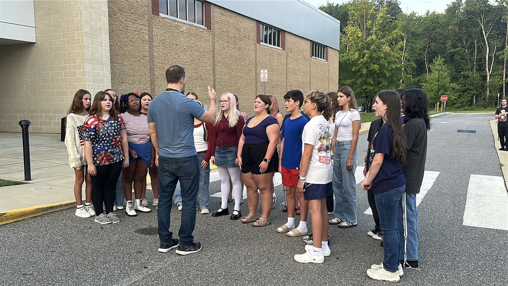 A student chorus group sings the national anthem during a 9/11 ceremony held in front of a middle school.
