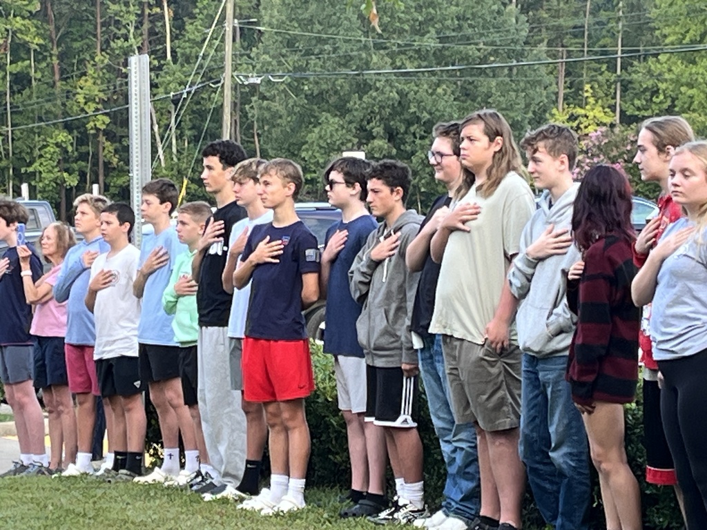 Students  recite the pledge of allegiance during a 9/11 ceremony held in front of a middle school.