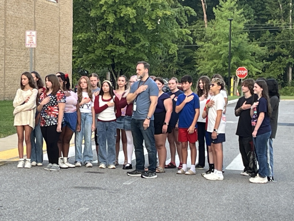Students  recite the pledge of allegiance during a 9/11 ceremony held in front of a middle school.