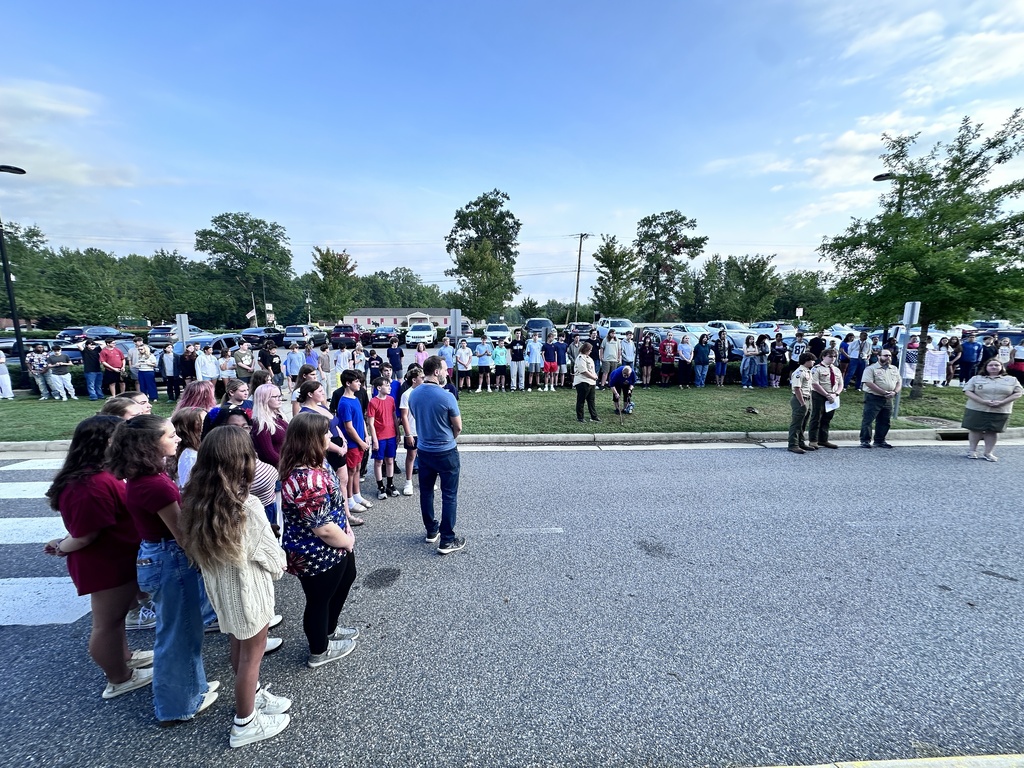 Students  recite the pledge of allegiance during a 9/11 ceremony held in front of a middle school.