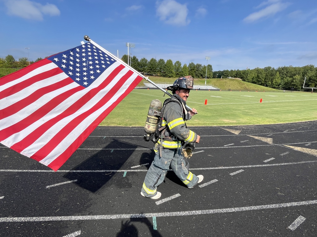 A firefighter in turnout gear carrying a flag walks laps to participate in a 9/11  remembrance ceremony held at the high school. 