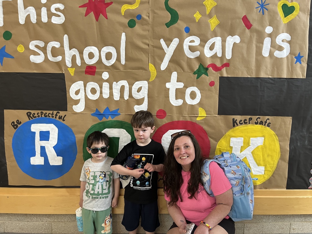 An adult and two children pose for a photo at a school open house event. 