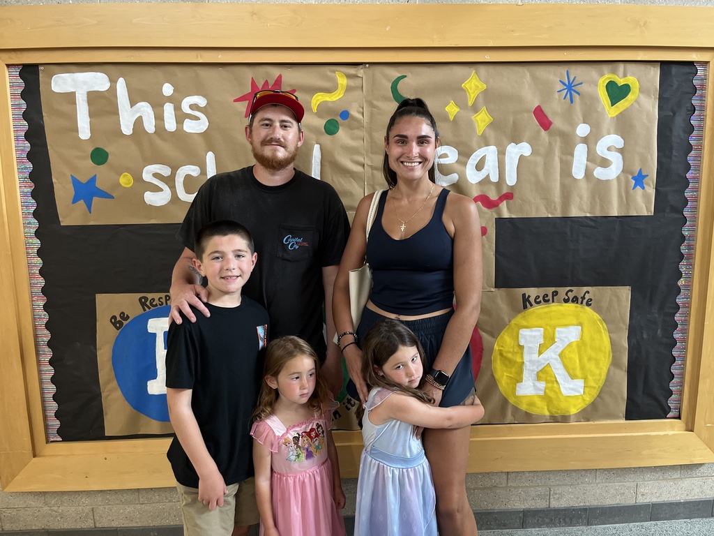 Two adults and three children pose for a photo at a school open house event. 