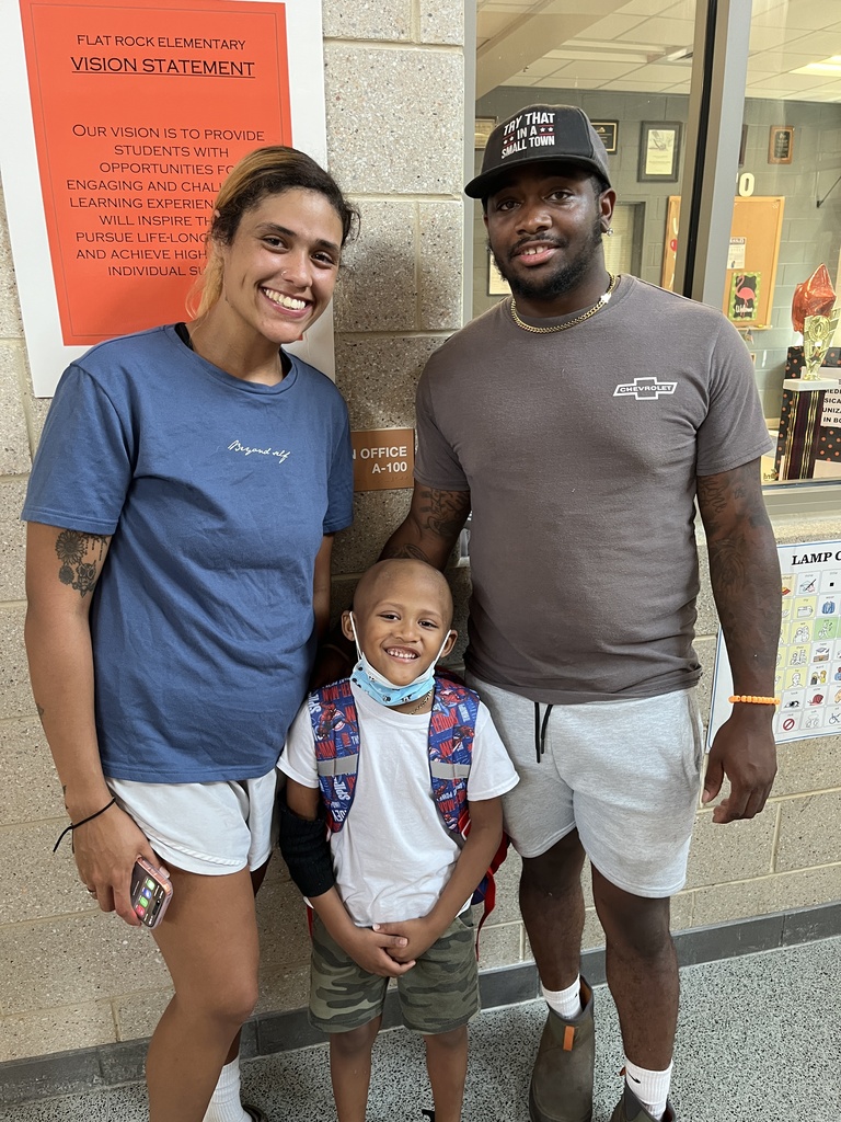 Two adults and one child pose for a photo at a school open house event. 