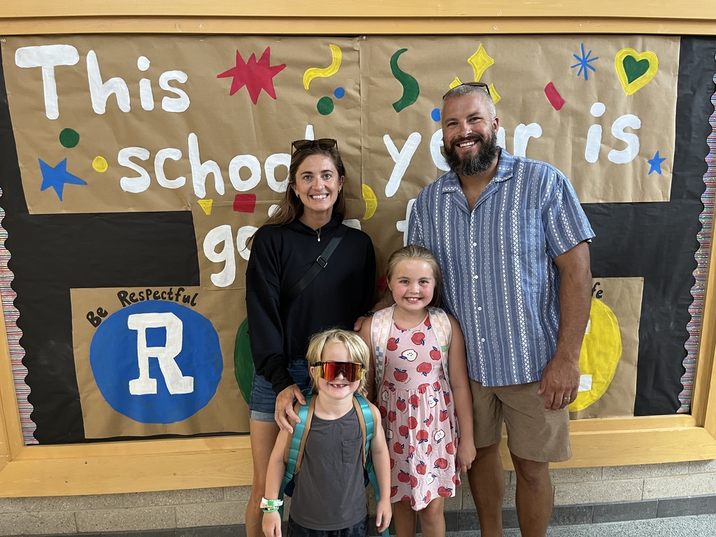 Two adults and two children pose for a photo at a school open house event. 