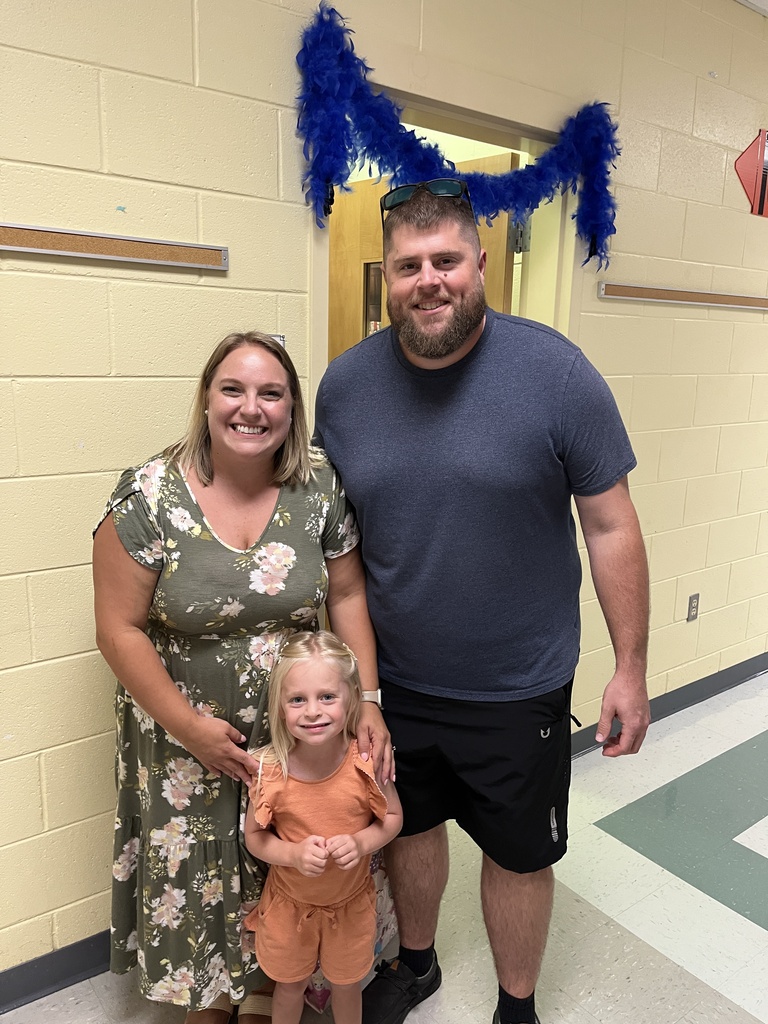 Two adults and a child pose for a photo at a school open house event. 