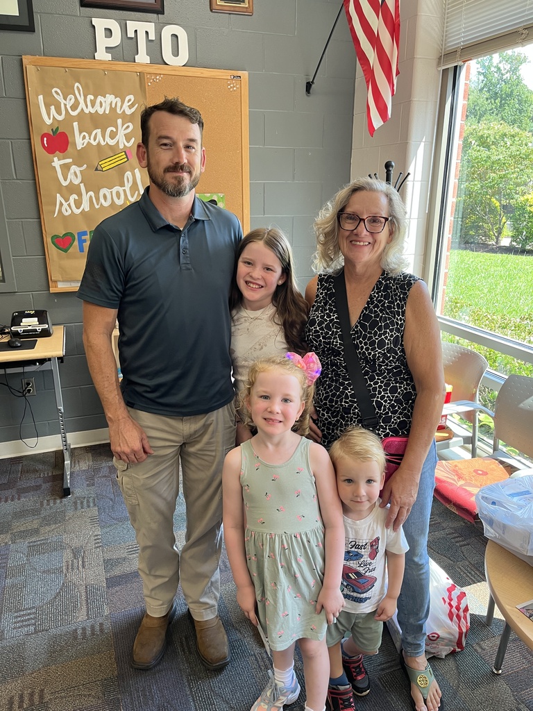 Two adults and three children pose for a photo at a school open house event. 