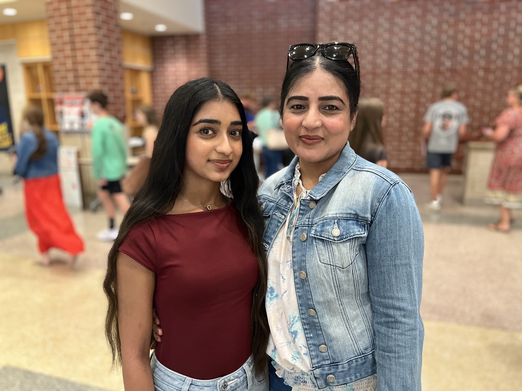 An adult and a teen pose for a photo at a high school open house event.