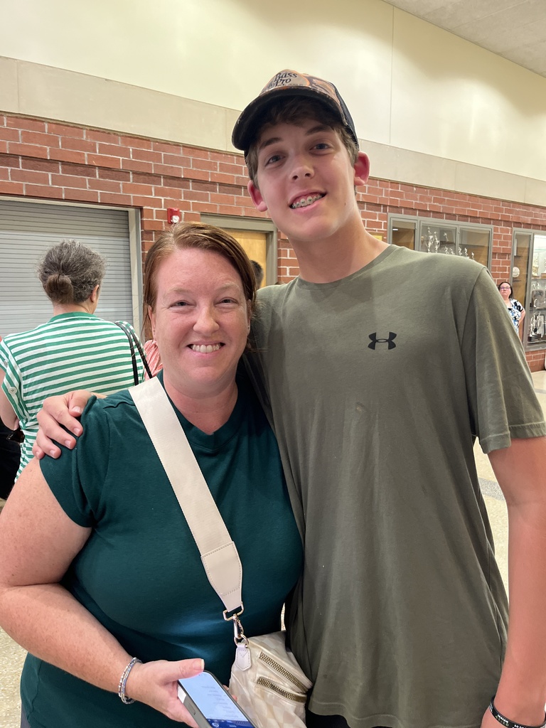 An adult and a teen pose for a photo at a high school open house event.