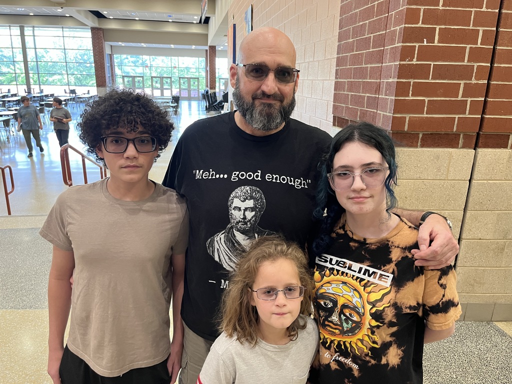 An adult and three students pose for a photo at a high school open house event.