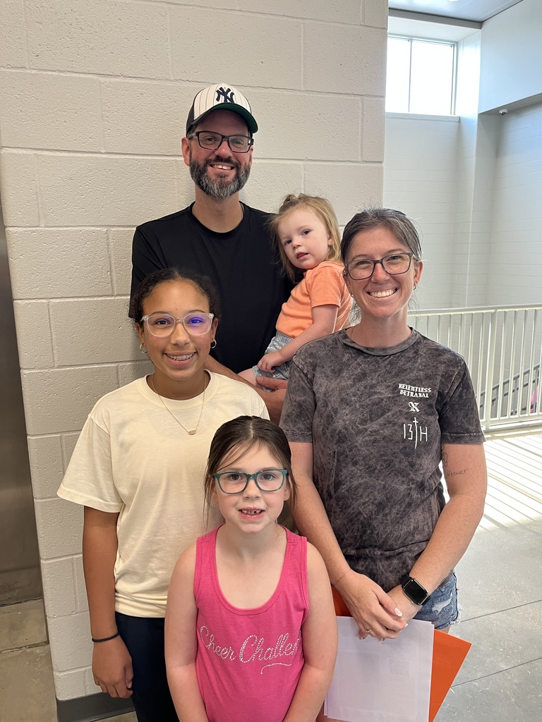 Two adults and three children pose for a photo at a middle school open house. 