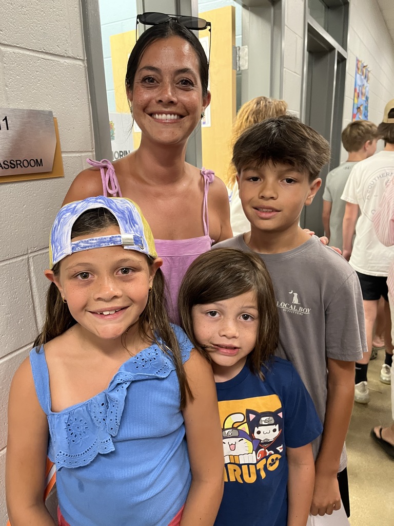 An adult and three children pose for a photo at a middle school open house. 
