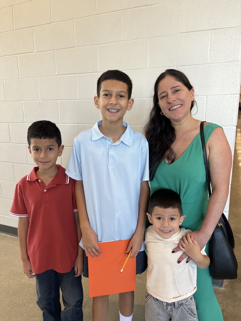 An adult and three children pose for a photo at a middle school open house. 