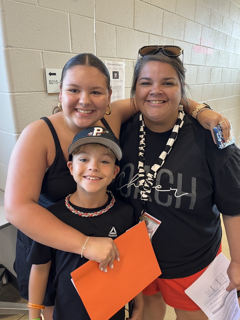 An adult and two children pose for a photo at a middle school open house. 
