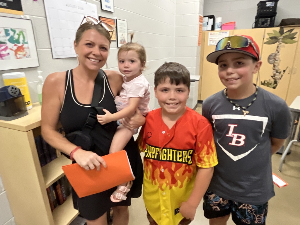 An adult and three children pose for a photo at a middle school open house. 