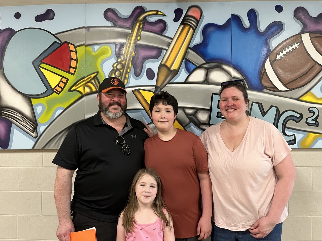 Two  adults and two children pose for a photo at a middle school open house. 