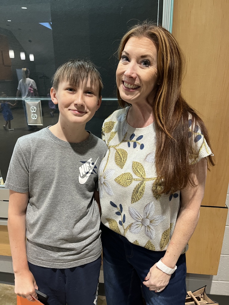 An adult and child pose for a photo at a middle school open house. 