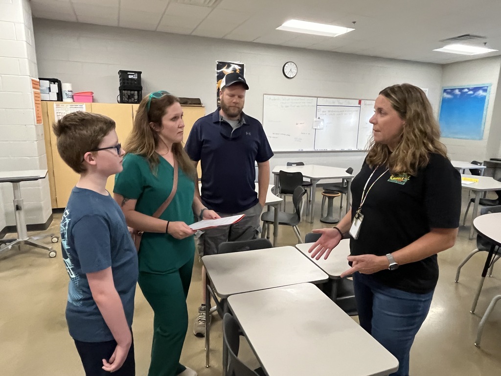 A middle school staff member gives information to a family at a middle school open house. 