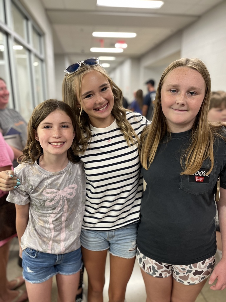 Three children pose for a photo at a middle school open house. 