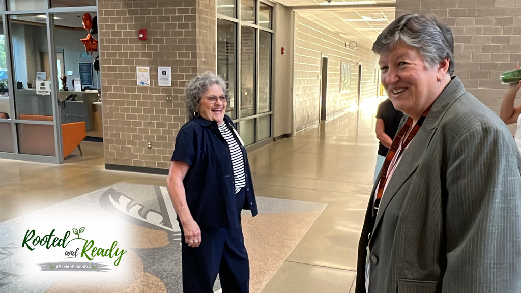 A school board member talks with the superintendent. Text embedded in photo: Rooted and Ready. 