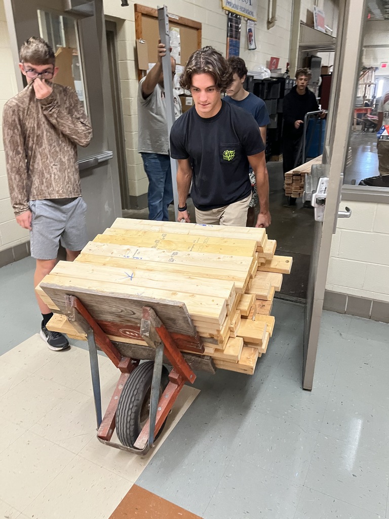 Building trades students carry wood that will be used to build electricity booths