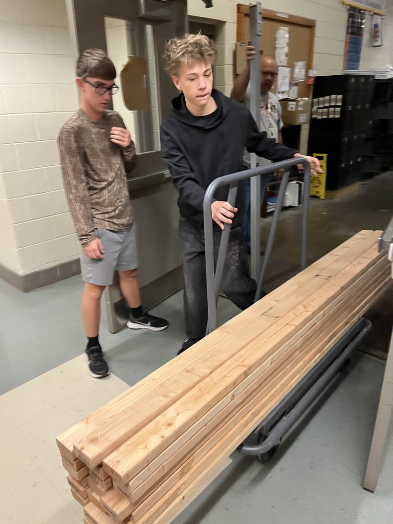 Building trades students carry wood that will be used to build electricity booths