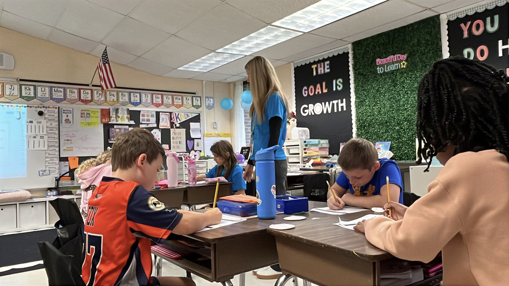 Students brainstorm ideas for a writing prompt about how to stay out of trouble . A teacher observes.