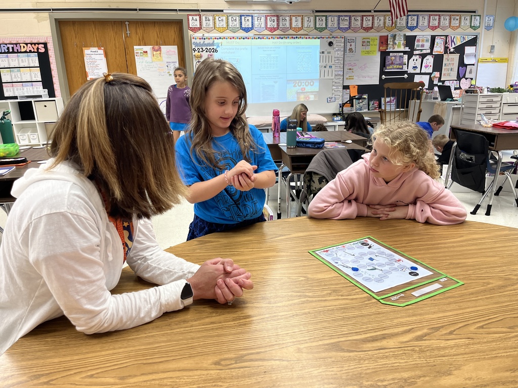 Students work  in groups to play games focused on prefixes before turning their attention to writing. A teacher observes. 