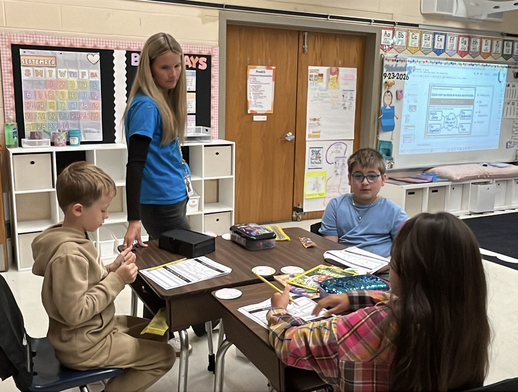 Students brainstorm ideas for a writing prompt about how to stay out of trouble . A teacher observes.