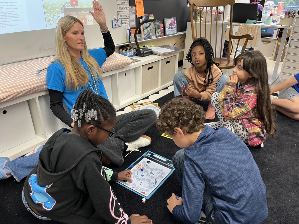 Students work  in groups to play games focused on prefixes before turning their attention to writing. A teacher observes. 