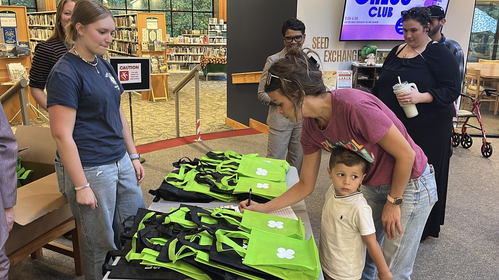 Parents sign their children in  at a preschool literacy event at a library. Children checking in receive a goodie bag.