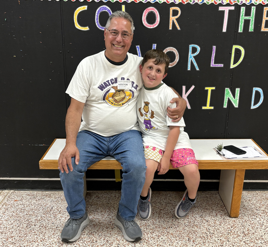 A man wearing a Watchdog t-shirt photos for a photo with a student.