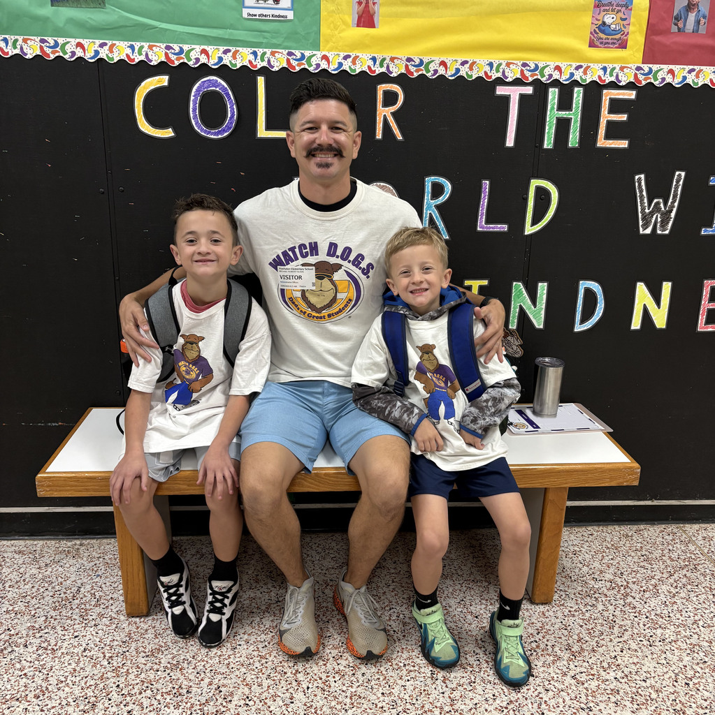 A man wearing a Watchdog t-shirt photos for a photo with two students.