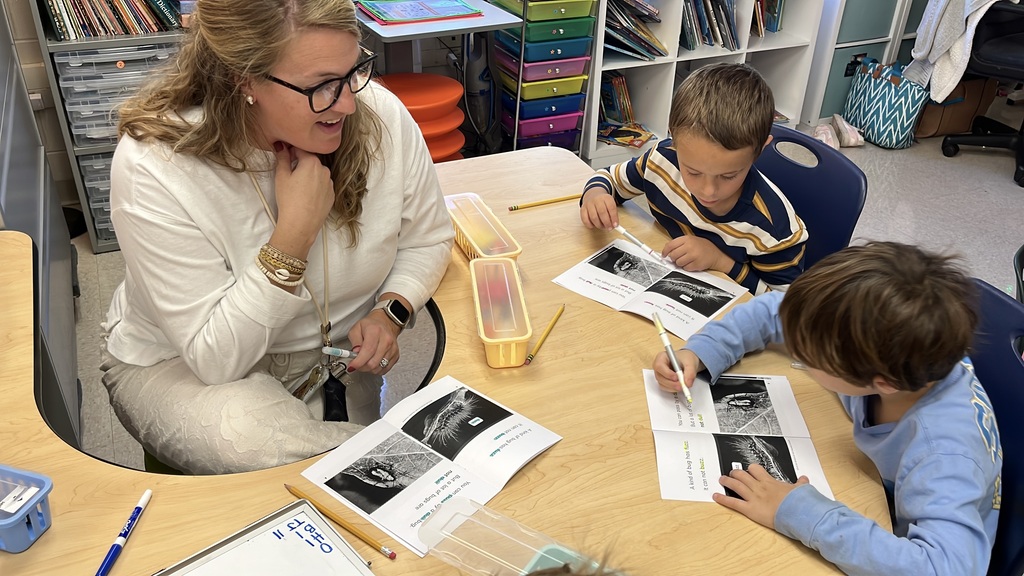 A teacher works with a group of students at a language arts station.