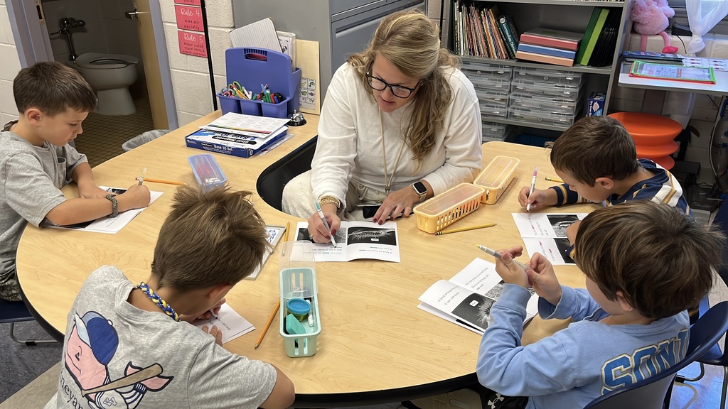 A teacher works with a group of students at a language arts station.