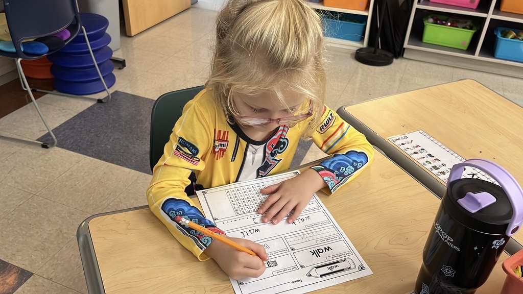 A student whose class is rotating to different language arts stations works on an assignment.