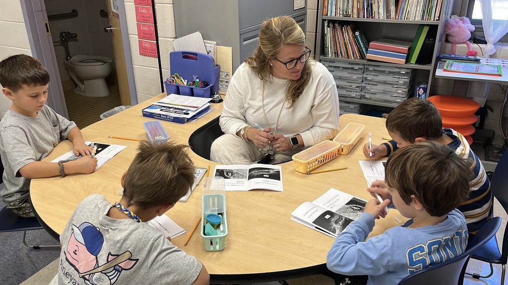 A teacher works with a group of students at a language arts station.